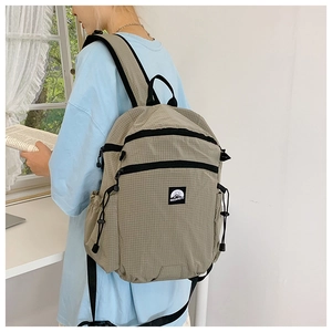 Detailansicht eines khakifarbenen Karo-Rucksacks mit verstellbaren Kordelzug-Seitentaschen