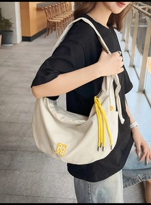 Detail der cremefarbenen Hobo-Tasche mit gelber RG-Stickerei und Quasten-Akzenten