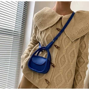 Detail of royal blue mini handbag styled with a cozy beige knit sweater