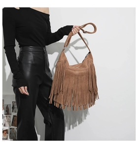 Detail shot of brown suede hobo bag with long bohemian tassels and wide shoulder strap