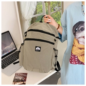 Detail eines karierten Nylon-Rucksacks mit Doppelreißverschluss und Kordelzug-Seitentasche