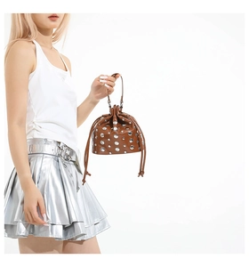 Detailed shot of brown leather bucket bag with silver rivets and drawstring closure