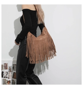 Detail of bohemian brown suede crossbody bag featuring long stylish fringe tassels