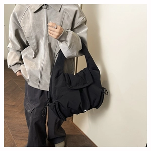 Detail of a black quilted puffer tote bag featuring drawstring sides and soft texture