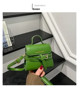 Detail of green faux leather mini crossbody bag with gold text and buckled flap