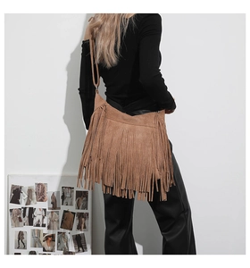 Close-up of brown suede tote bag with long fringe tassels shown on a female model