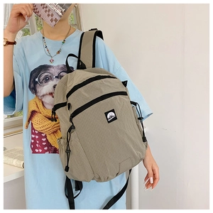 Detailansicht des khakifarbenen Karo-Rucksacks mit reißfestem Stoff und Berg-Logo-Aufnäher