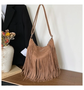 Detail of bohemian brown suede tote bag featuring fringe tassels in artistic studio setting