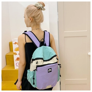 Detailansicht eines stylischen Schulrucksacks mit Farbmuster, getragen auf gelber Treppe