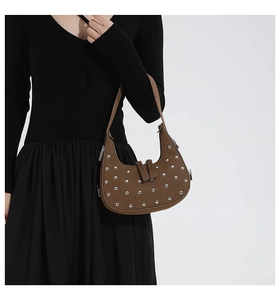 Detail of brown suede baguette bag featuring silver studs and retro crescent silhouette