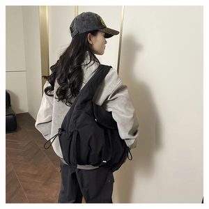 Detail view of large black waterproof nylon tote bag with drawstring closure and side pockets