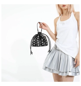 Detail of black drawstring bucket bag featuring polished silver rivet studs decoration
