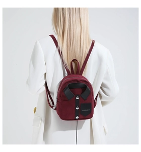 Detail of creative shirt-shaped burgundy mini backpack on model's back with fashion branding