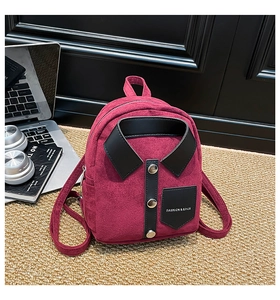 Detail of burgundy shirt-style backpack with black collar and silver buttons on woven carpet