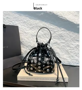 Detailed view of black bucket bag with silver studs and drawstring on books