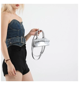 Detail of silver metallic mini shell bag with mirror finish and buckle strap detail