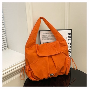 Detail of orange nylon shoulder bag featuring drawstring pockets and woven brand label