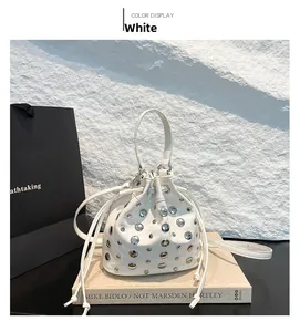 Detailed close-up of white bucket bag with silver metal rivets and drawstring closure