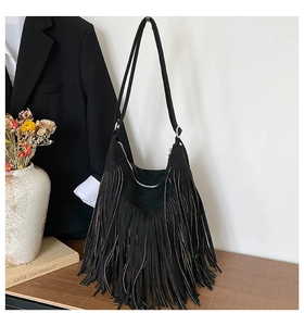 Detail of black suede hobo bag featuring long tassels and adjustable silver metal buckle