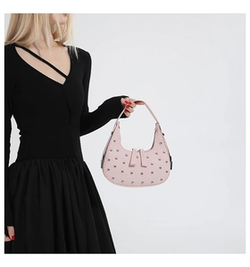 Detail view of pink crescent handbag with silver rivets on a minimalist black dress