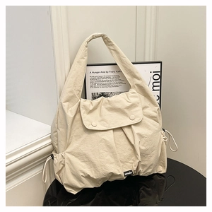 Detail of cream large capacity tote bag featuring nylon texture and side drawstring