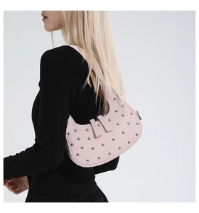 Close-up of pink crescent shoulder bag with silver rivets and dual zipper details