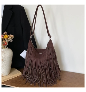Detail of dark brown suede hobo bag featuring long bohemian fringes and metal rings