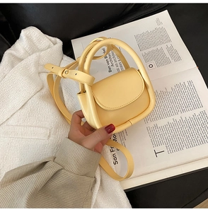 Detailed shot of a yellow mini leather handbag with a top handle and adjustable strap