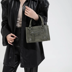 Green vintage rivet motorcycle shoulder bag with studs and dual handles on a model