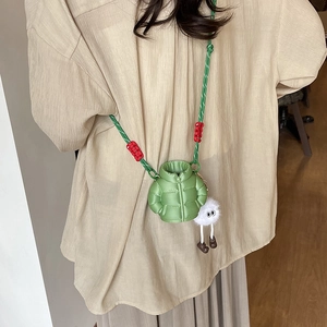 Mini green puffer crossbody bag with colorful woven strap and cute plush monster charm