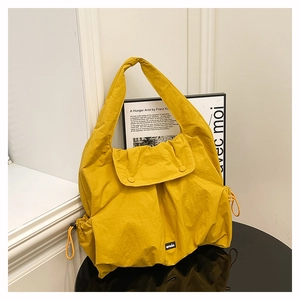 Detail of yellow nylon tote bag featuring drawstring accents and dual magnetic snap closure
