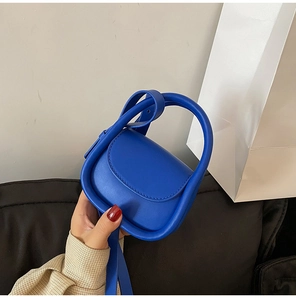 Detail of Klein blue mini handbag with curved top handles and matching crossbody strap