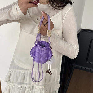 Mini purple puffer crossbody bag with plush doll charm shown on model