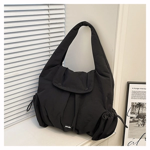 Detail of black quilted puffer shoulder bag featuring drawstring sides and a soft texture