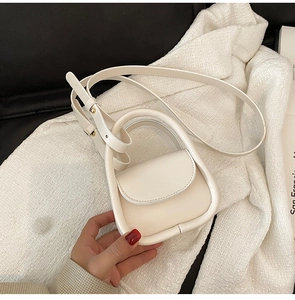 Detail of a creamy white mini handbag with circular handle and adjustable shoulder strap