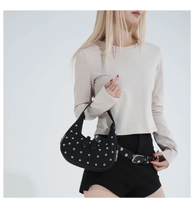 Close-up of black crescent shoulder bag featuring silver rivets and matching studded belt