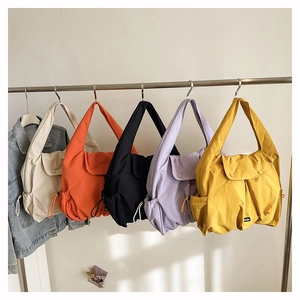 Detail view of large capacity nylon shoulder bags in five vibrant colors with drawstring sides