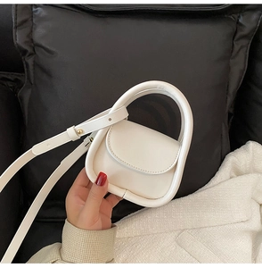 Close-up of white minimalist mini handbag showing smooth leather texture and stitching detail