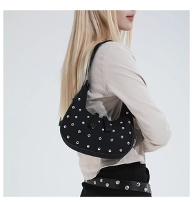 Detail of black crescent hobo bag featuring silver punk rivets and adjustable strap