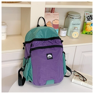Detailansicht eines lila-grünen Nylon-Rucksacks auf einem weißen Tisch in hellem Raum
