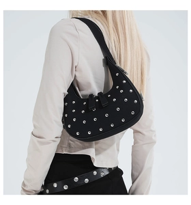 Detail of black crescent shoulder bag with silver metallic studs and punk aesthetic