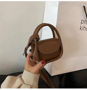 Detailed view of mini brown leather handbag with round handle and shoulder strap