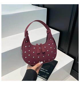 Detail of burgundy studded crescent bag with silver rivets and dual zipper closure