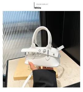 Detailed close-up of a mini white shell bag with metallic buckle and slim strap