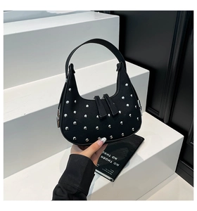 Detail of black crescent handbag featuring silver metal studs and double zipper closure