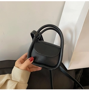 Close-up of a mini black leather handbag with round dual handles and a crossbody strap