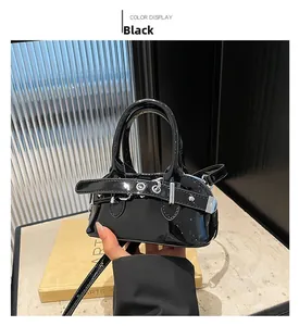 Detail view of glossy black mini shell bag with strap buckles and metallic stud accents