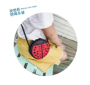 Vue détaillée du sac bandoulière coccinelle pour enfant en cuir rouge et noir