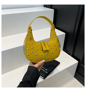 Detail of ginger yellow half-moon bag featuring silver studs and dual zipper design