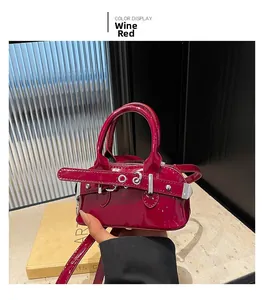 Close-up of wine red patent leather shell bag with silver buckle and metallic gloss